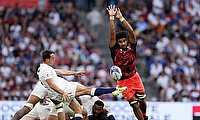 Alex Mitchell of England kicks the ball upfield whilst under pressure from Isoa Nasilasila of Fiji